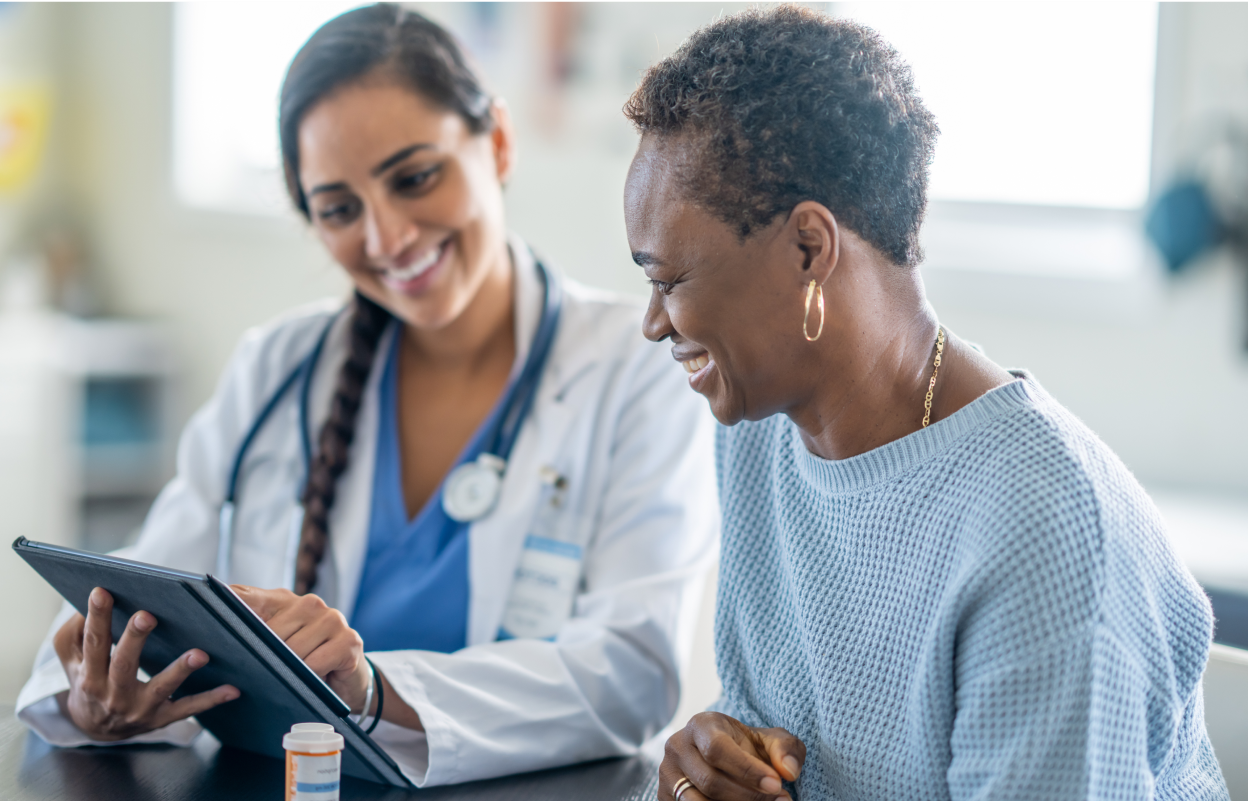 Smiling healthcare provider and patient sitting together, reviewing gut health information on a tablet, promoting the full gut health portfolio.