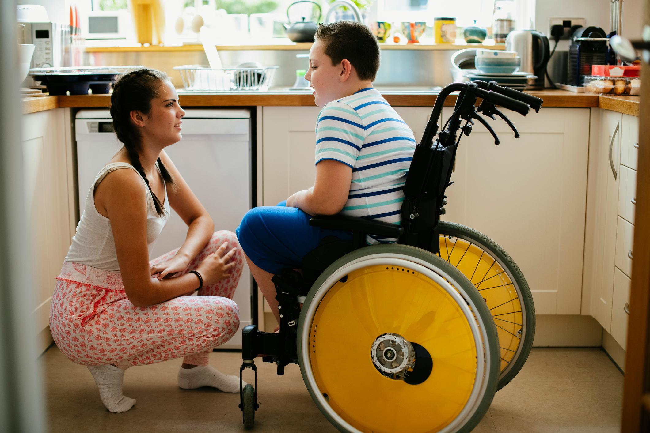 Sister talking to her disabled brother in the kitchen.