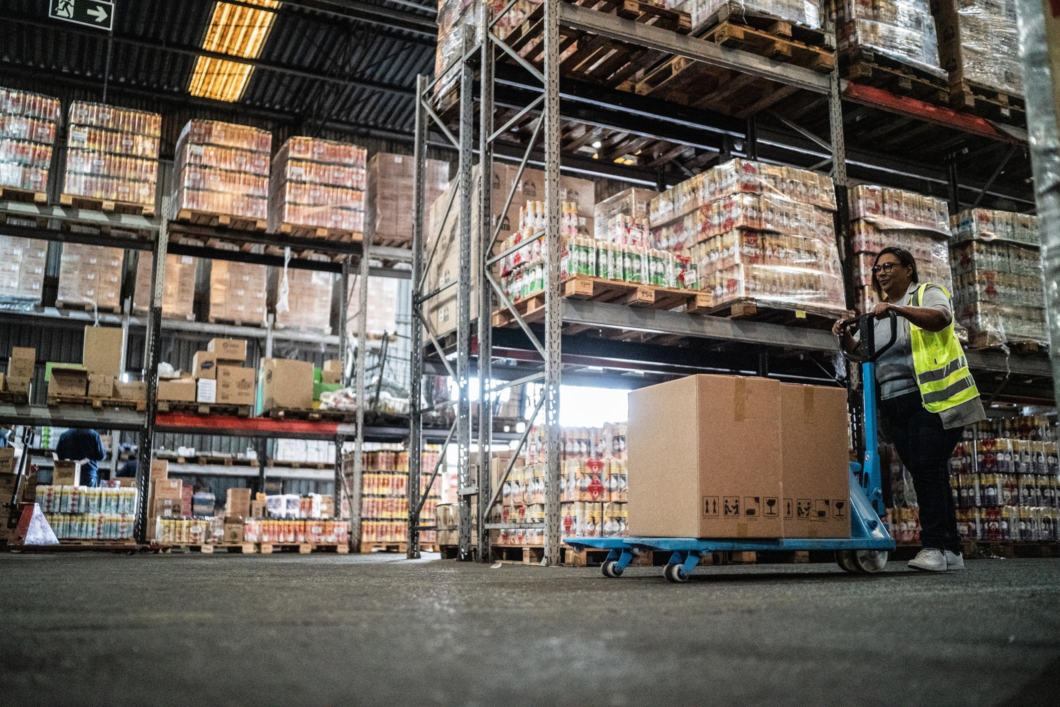 Warehouse worker wearing PPE using a pallet truck.