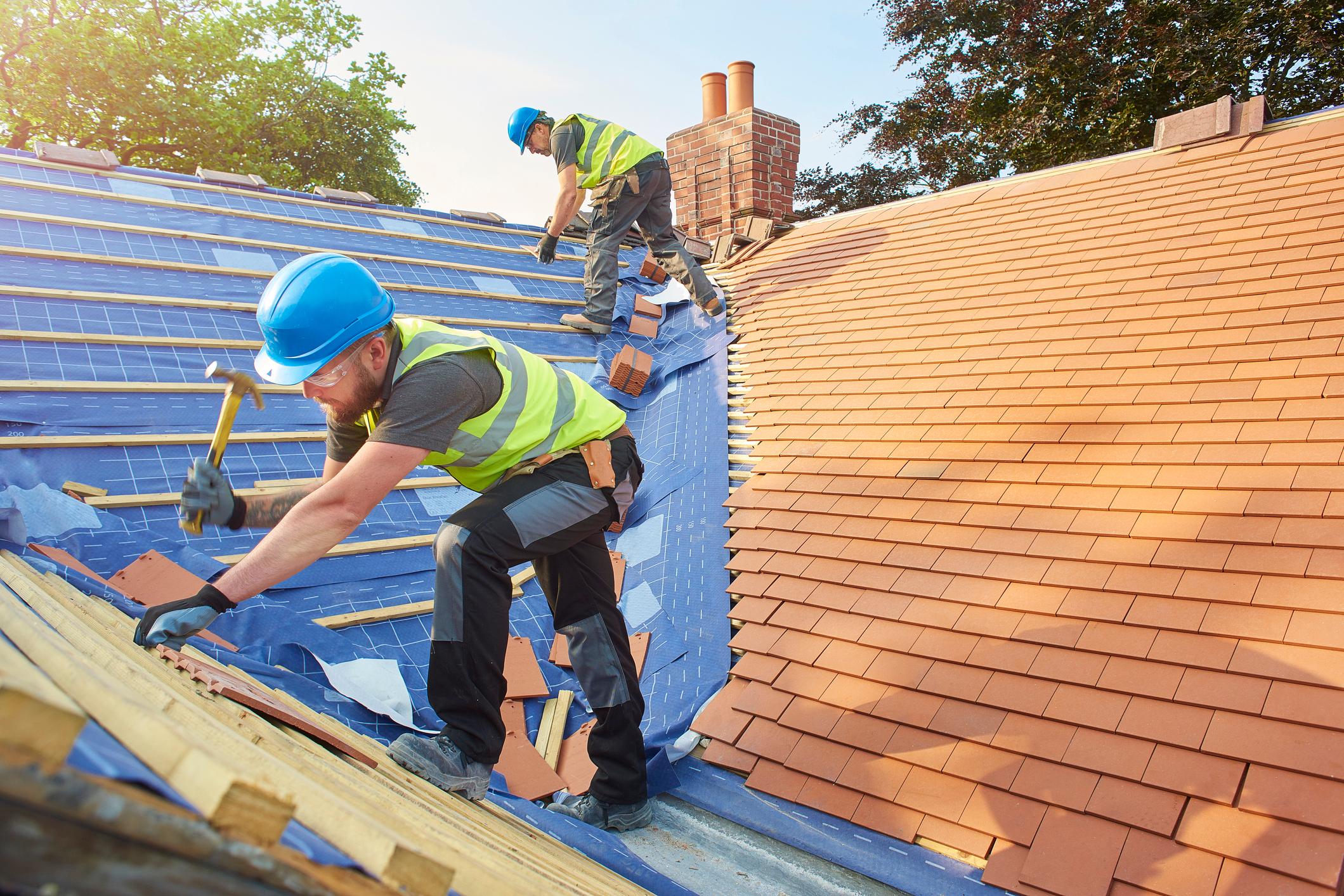 Two roofers constructing a roof.