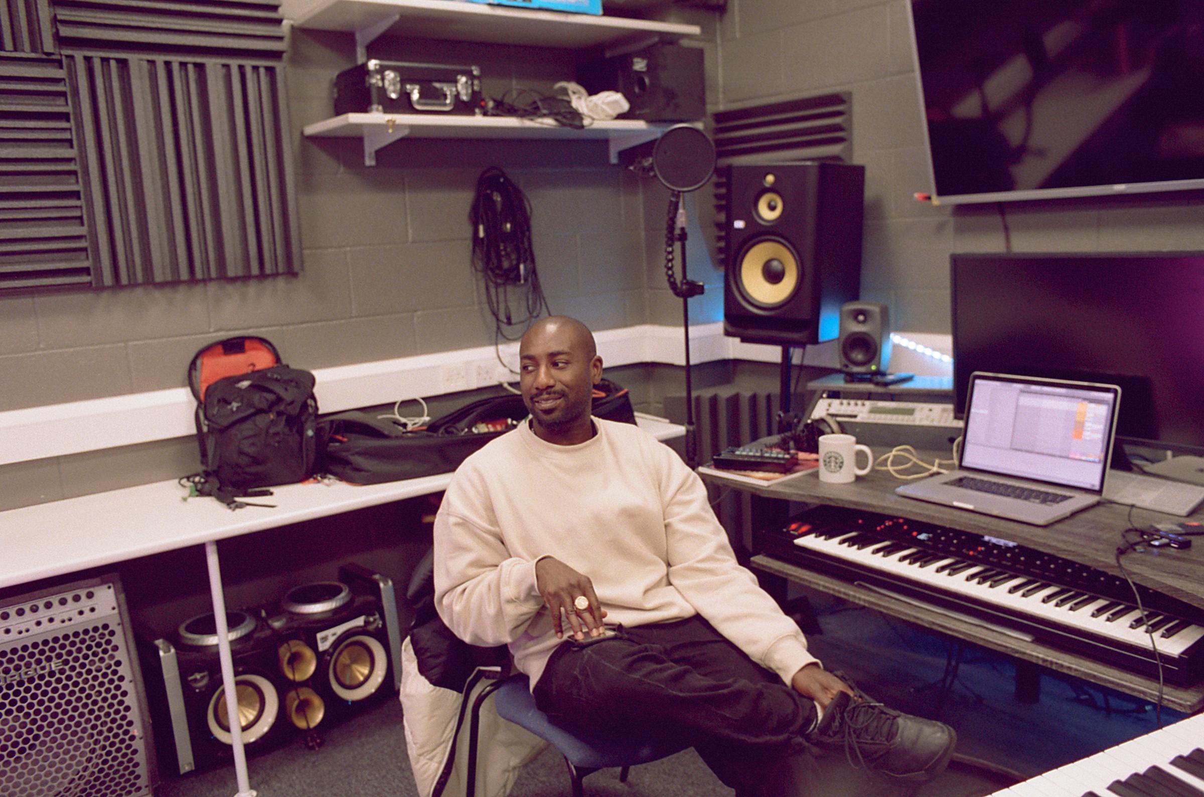 Music producer in a music studio sat on a chair.