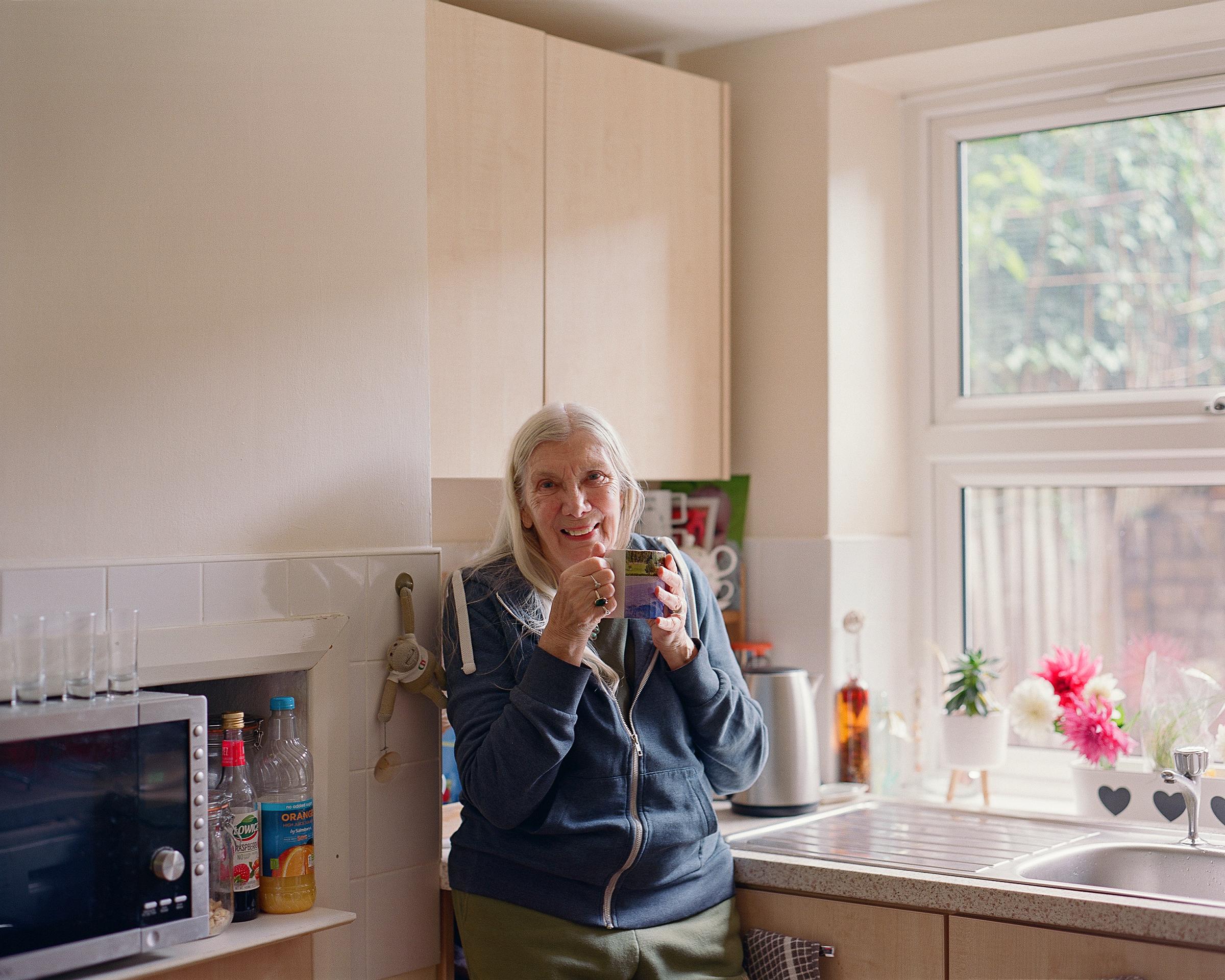 Smiling woman drinking a cup of tea in a kitchen.