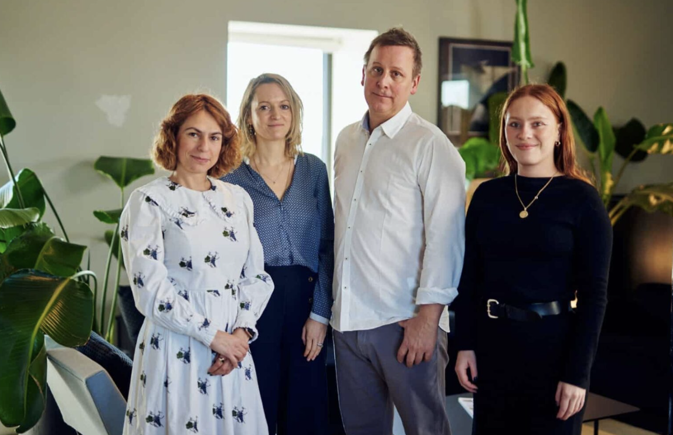 Four people in work attire standing and smiling for photo