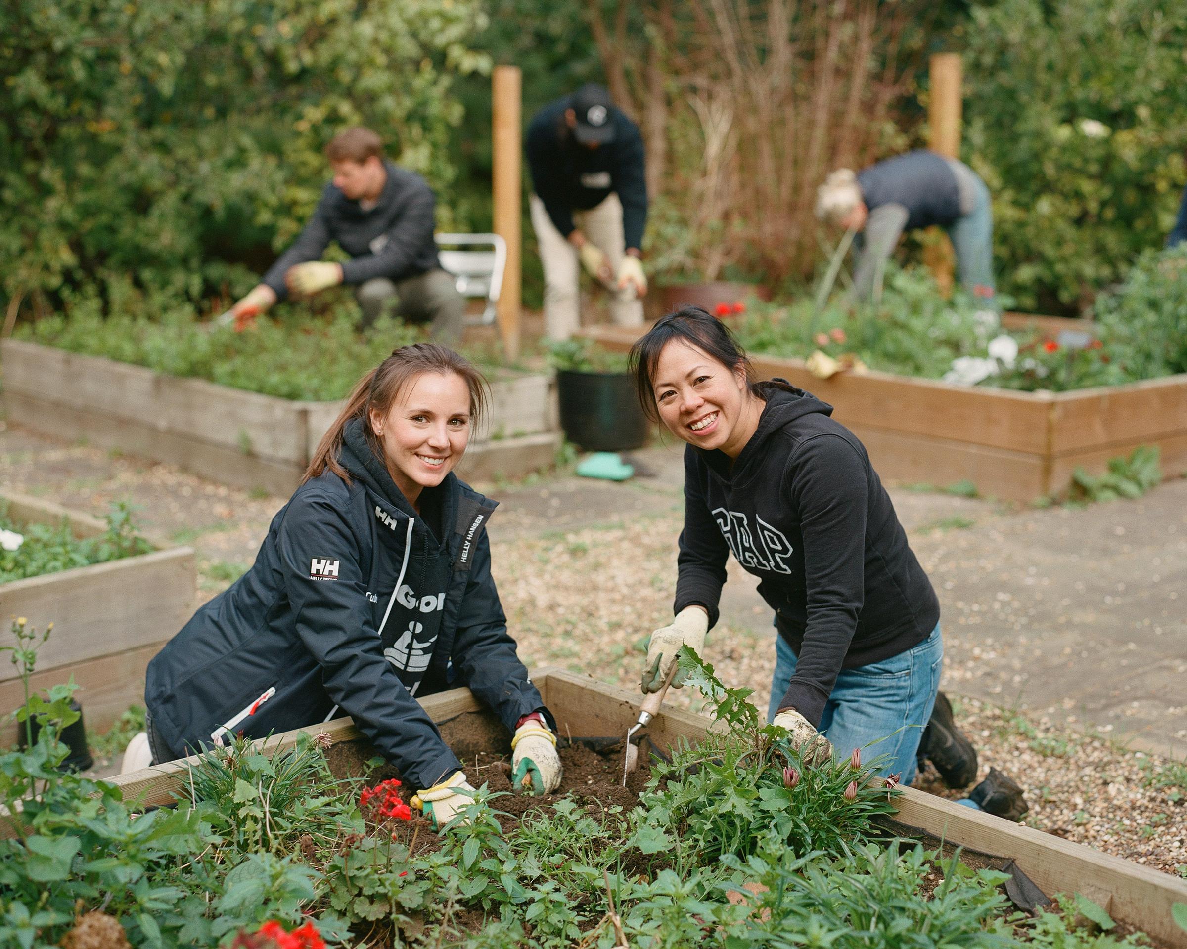 Volunteers tidying a school garden smiling at camera