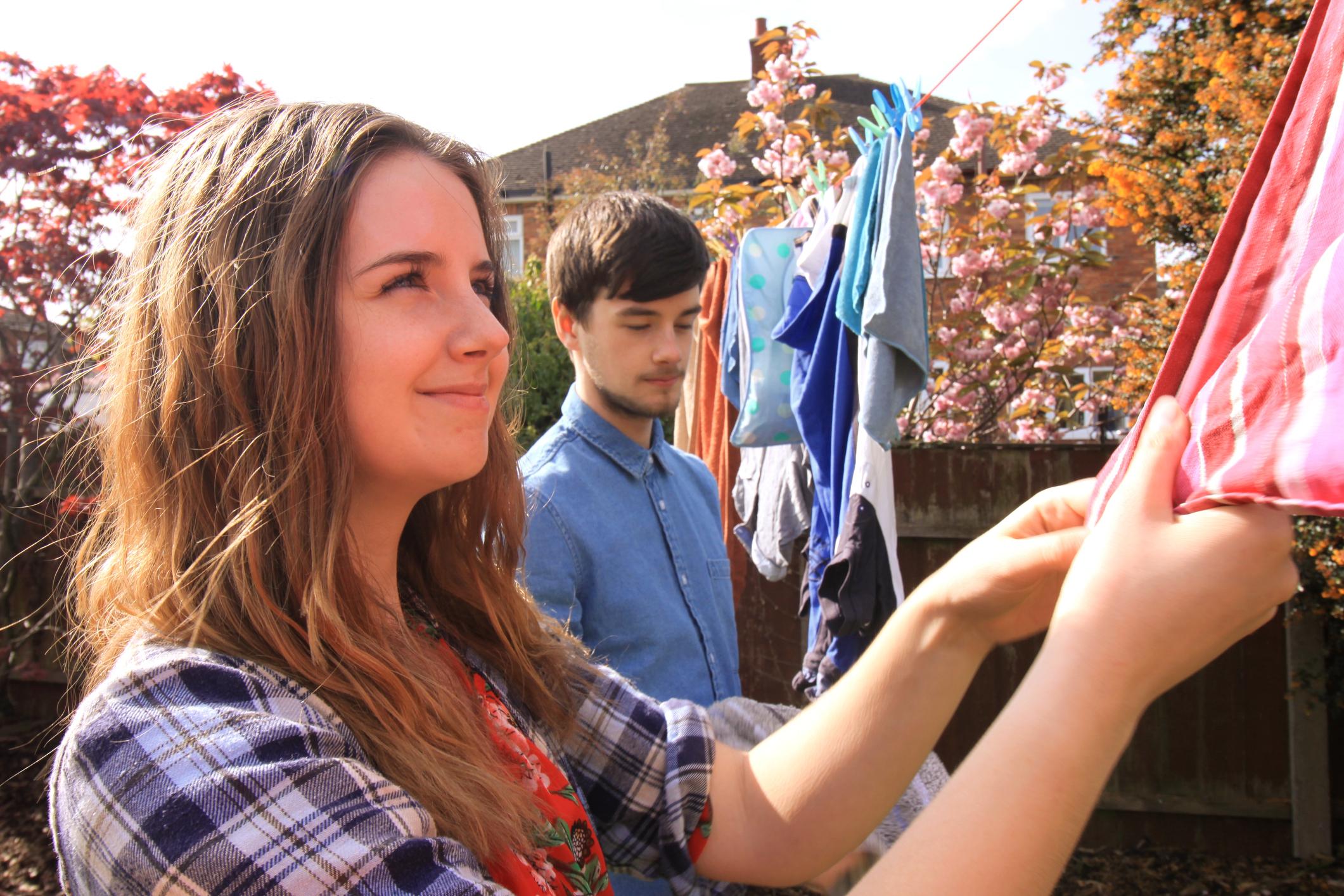 Two young people hanging out washing.