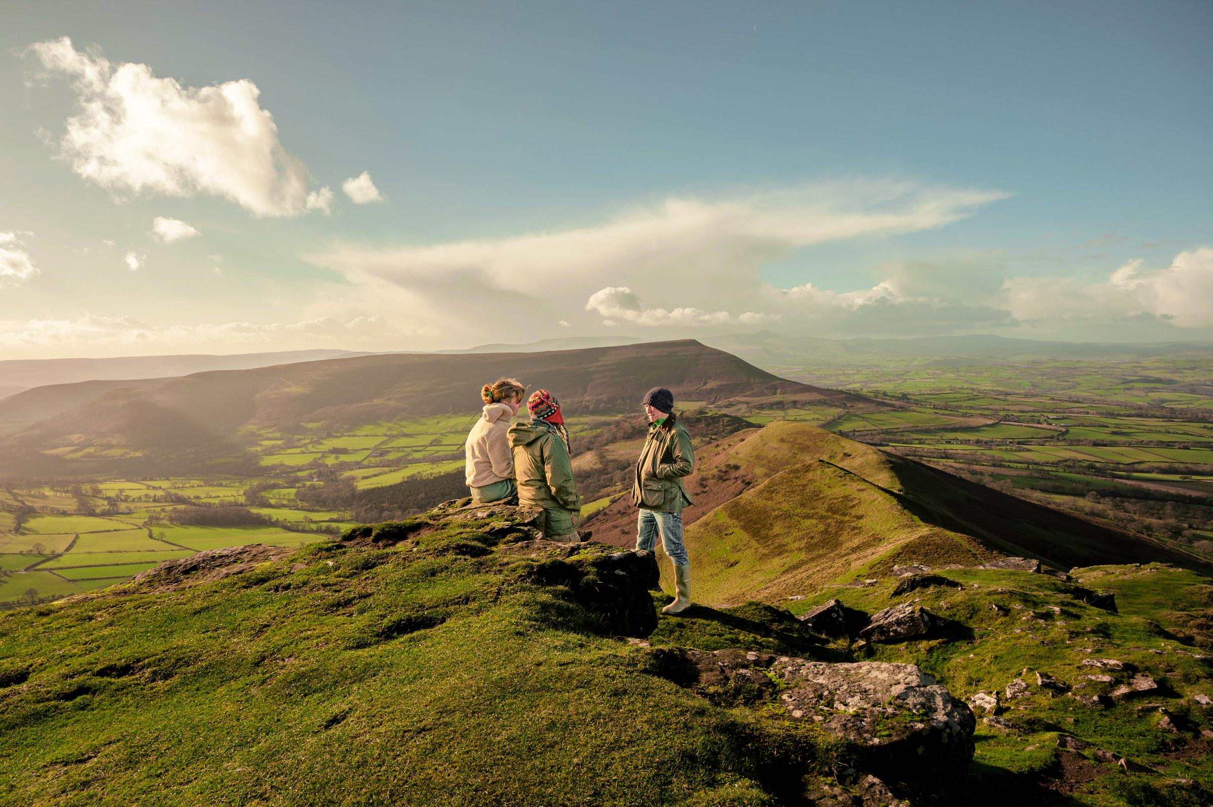 Three people at the top of a mountain in Wales