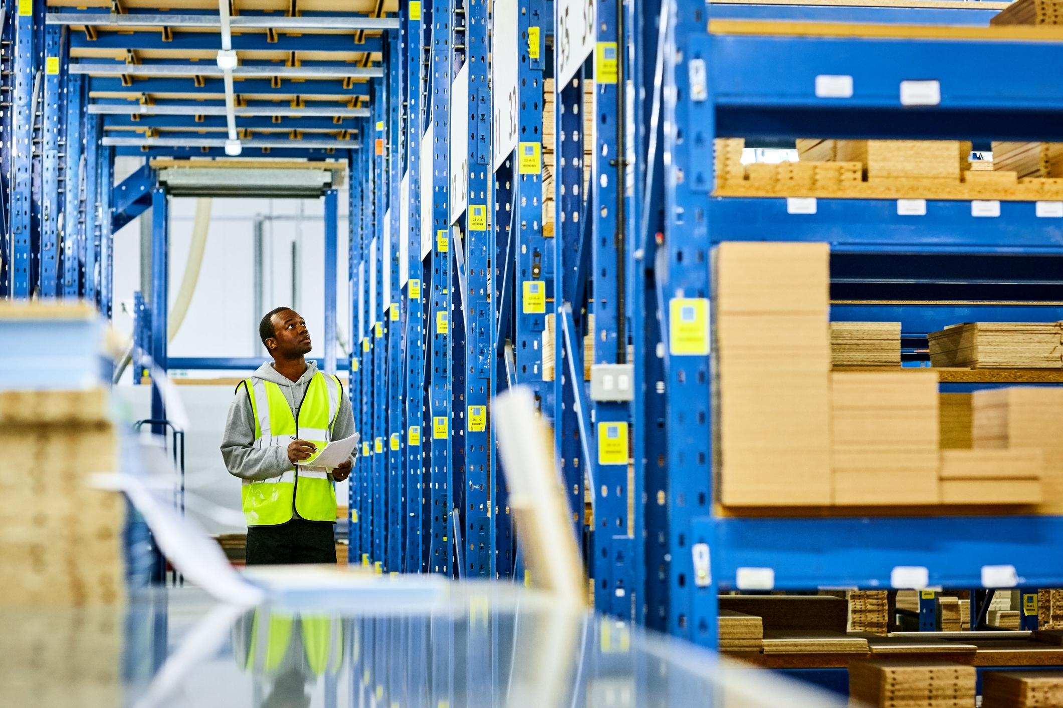 Warehouse worker with checklist taking inventory of products.