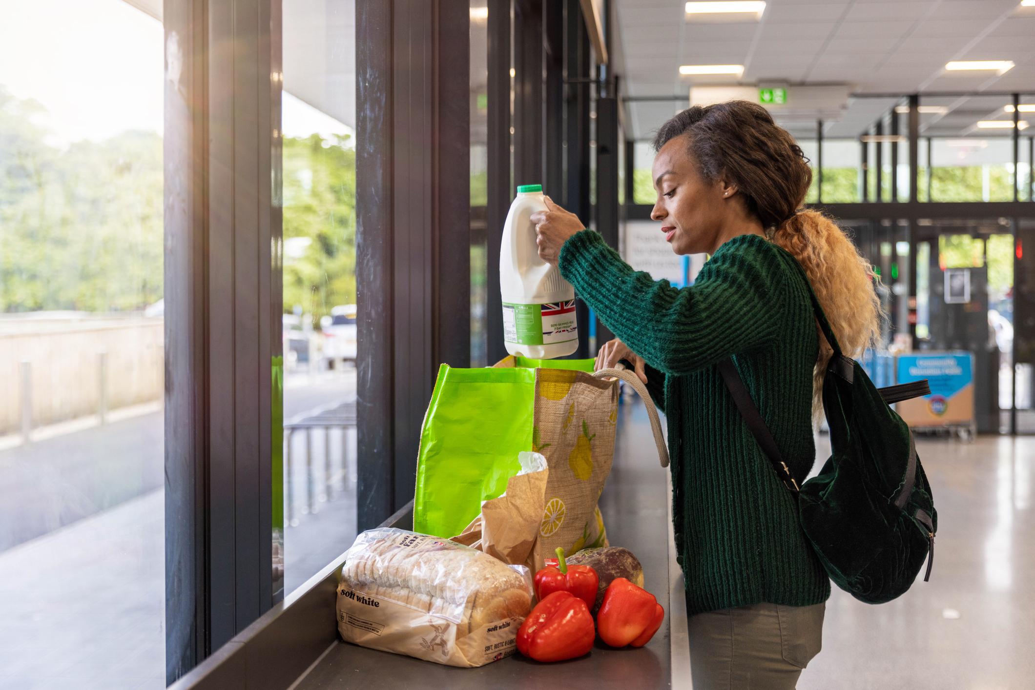 Woman packing her shopping into a reusable bag in a budget supermarket.