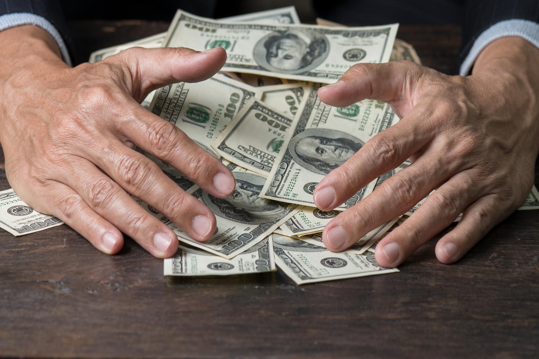 Man hands sweeping money,business concept. Lucky man winning  lots of us dollar from gambling,with smiling face and black background.