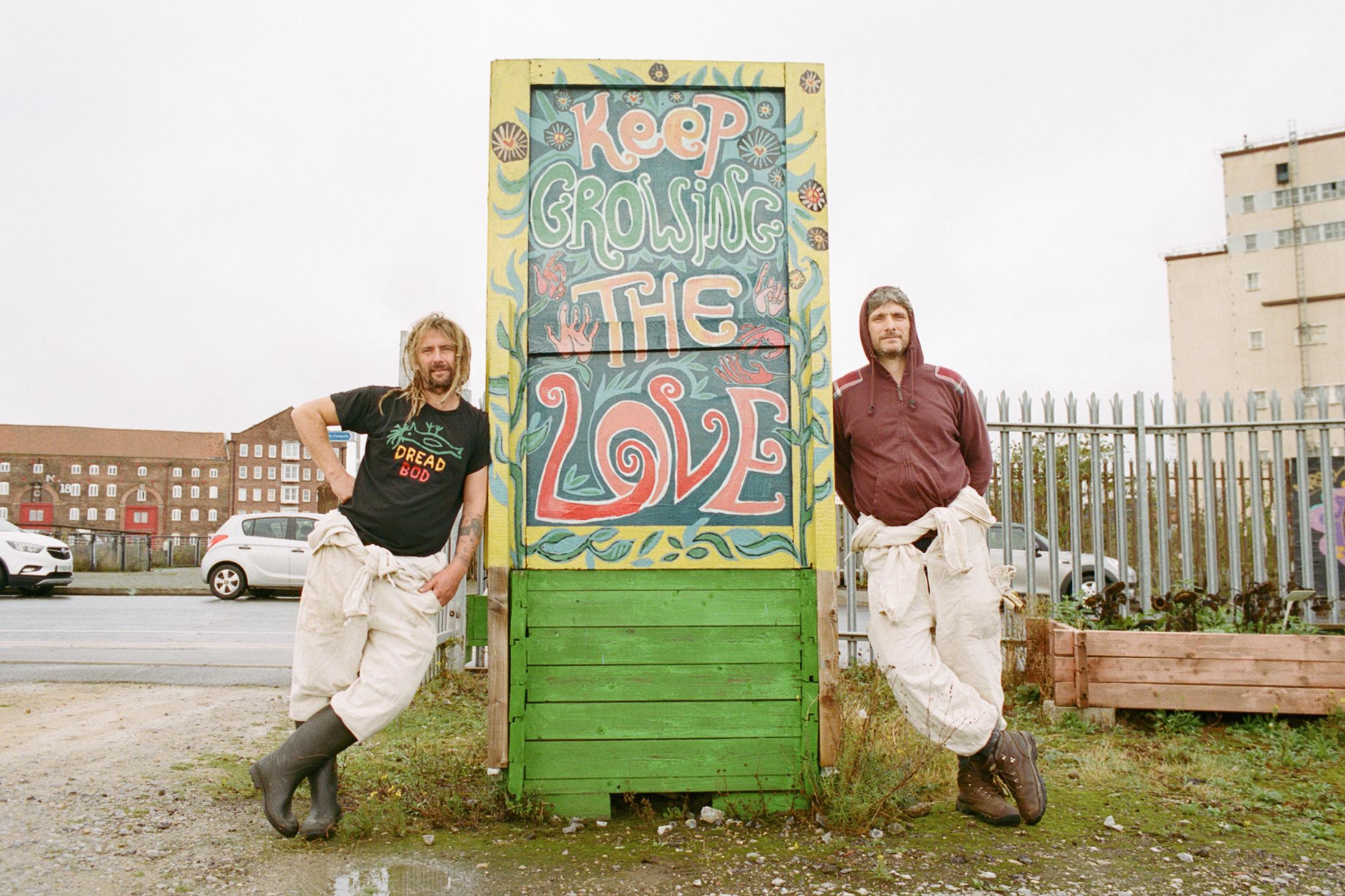 Two men standing next to a sign that says "keep growing the love".