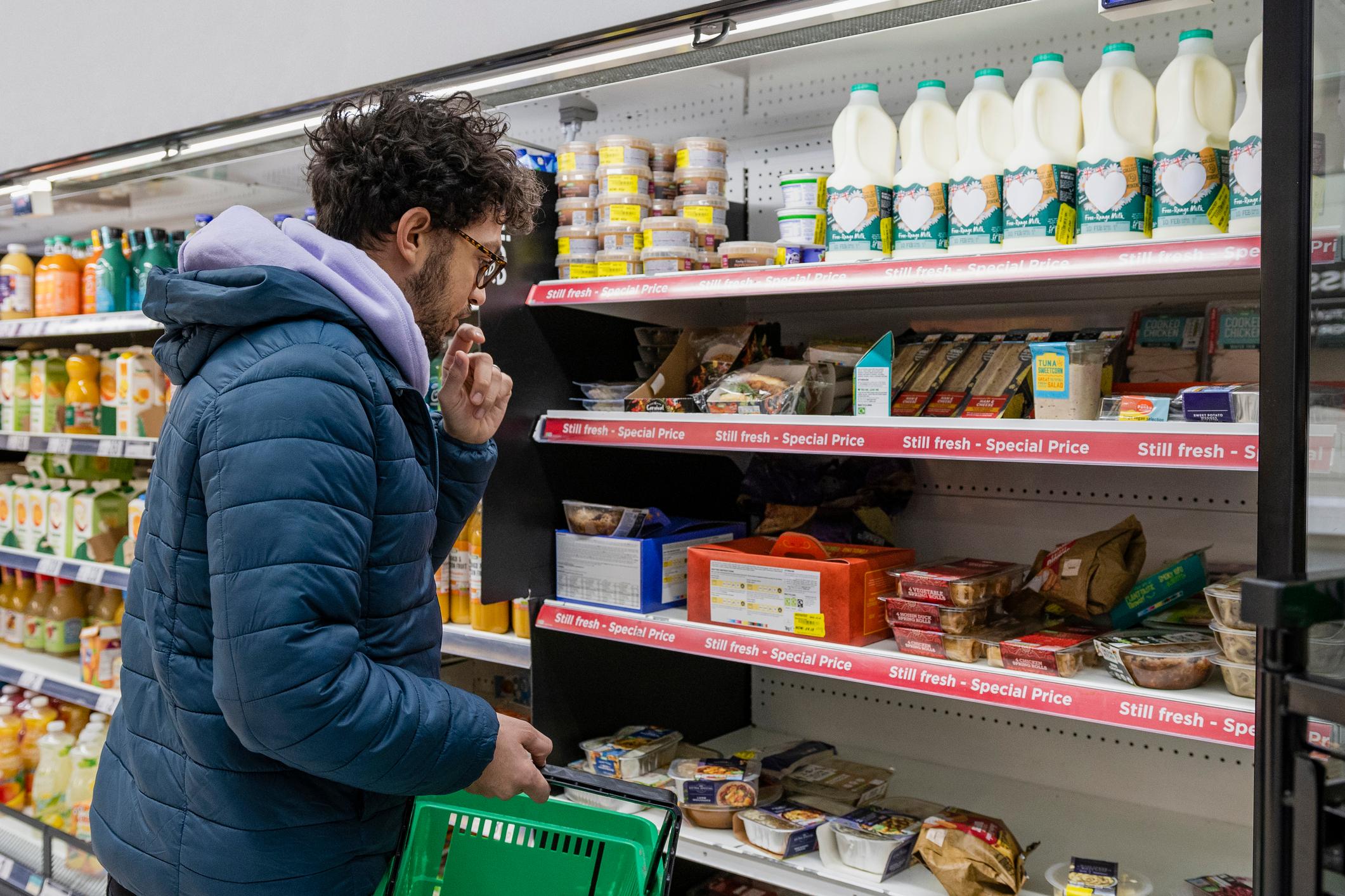 Man looking at reduced items on a shelf in a supermarket.