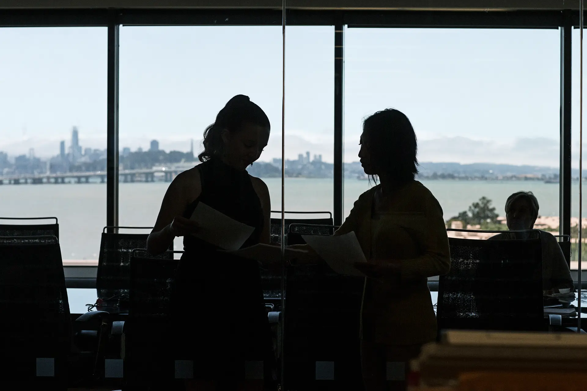 Employees looking at papers in office with skyline view of San Francisco