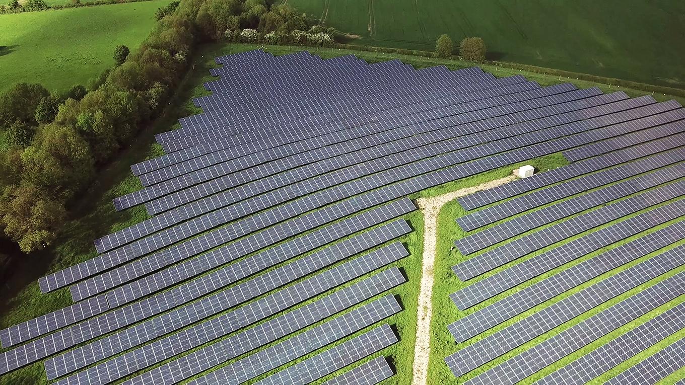 Solar panels farm between agriculture fields in aerial view.