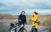 Two people with electric bikes standing in Amager Strandpark with the sea in the background