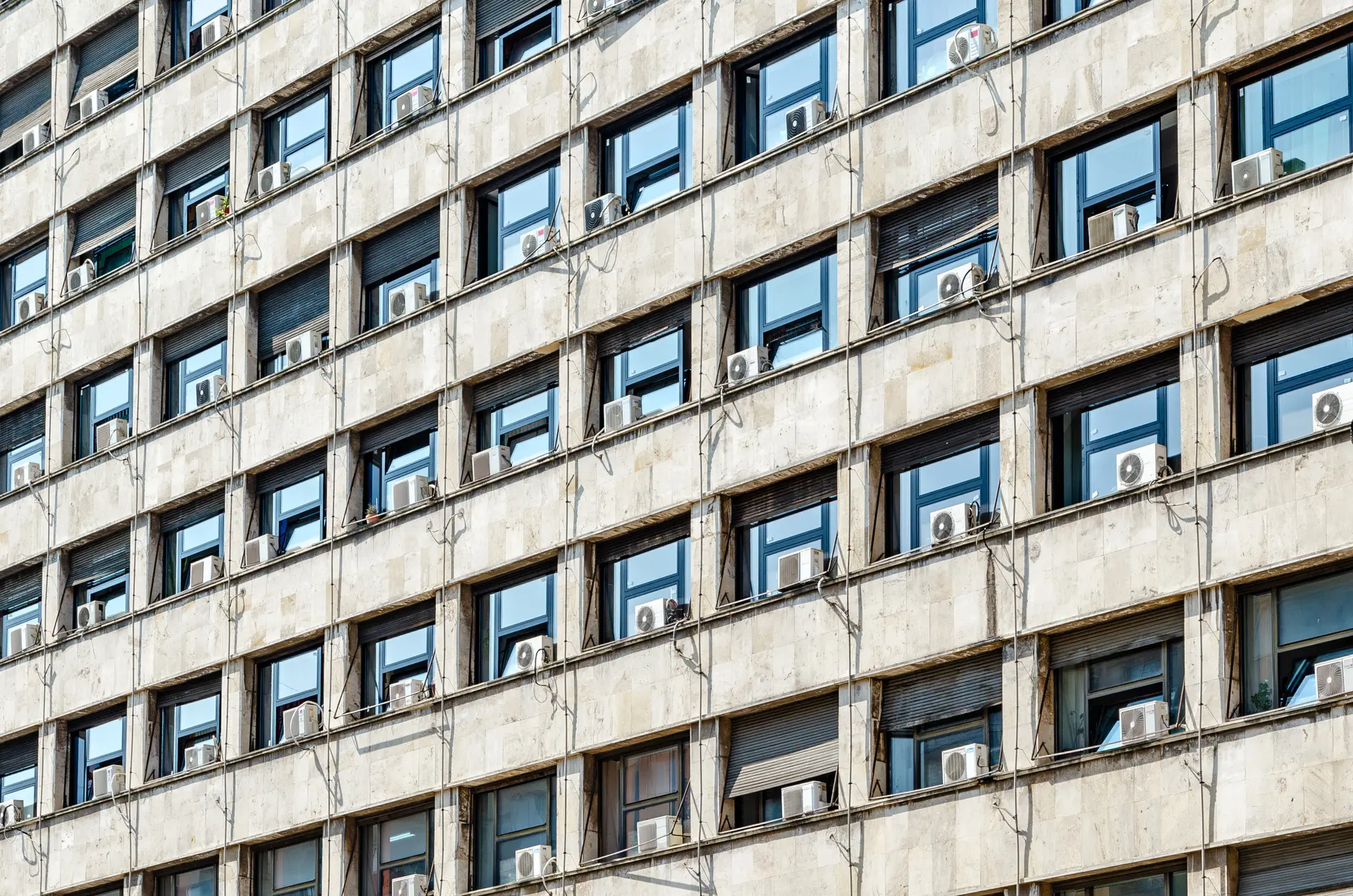 Office building with lots of air conditioning units installed outside in an organized mess