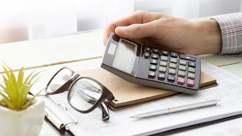 Close-up image of a man holding a calculator