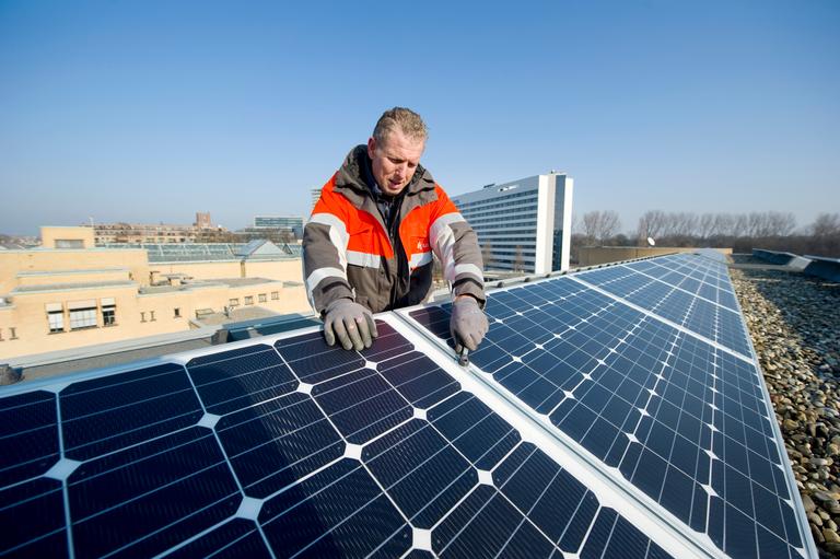 Installateur op dak met zonnepanelen