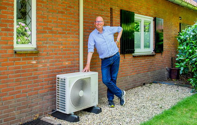 Warmtepomp eigenaar Jan Hoorn staat glimlachend naast de buitenunit van zijn hybride warmtepomp.