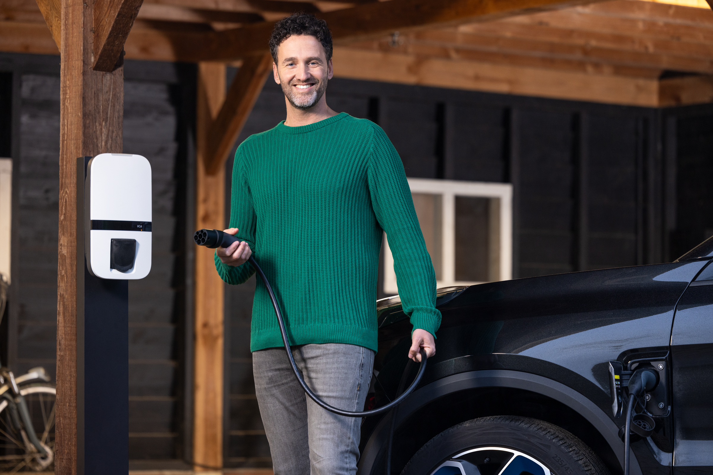 Man met laadstekker bij laadpaal