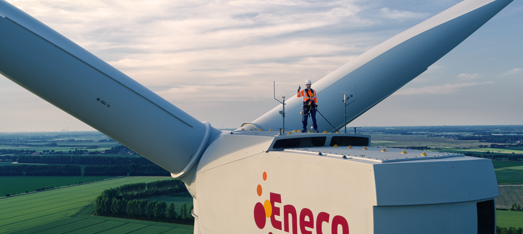 Eneco monteur staat op een windmolen