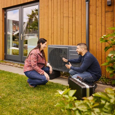 Eneco monteur en vrouw hurken buiten bij warmtepomp