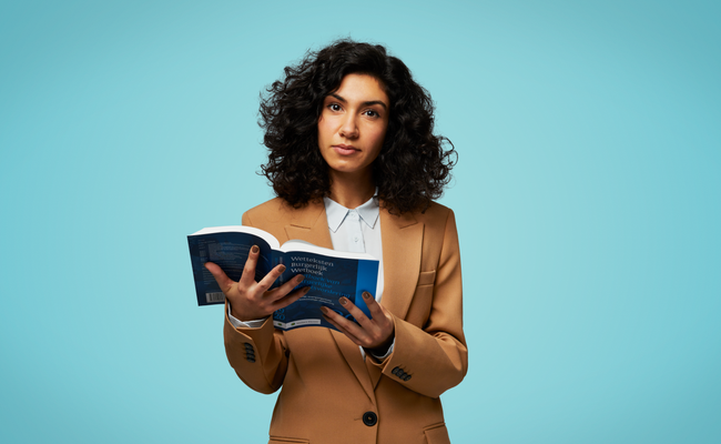Vrouw met wetboek in haar handen voor een blauwe achtergrond