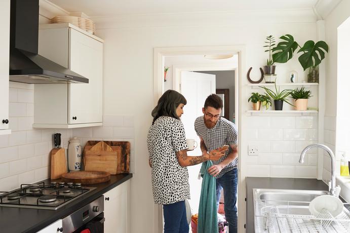 Twee mensen kijken naar een mobiele telefoon bij de wasmachine