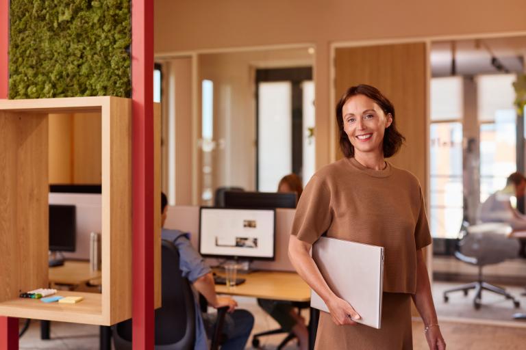Une femme d'affaires au bureau avec un ordinateur portable sous le bras