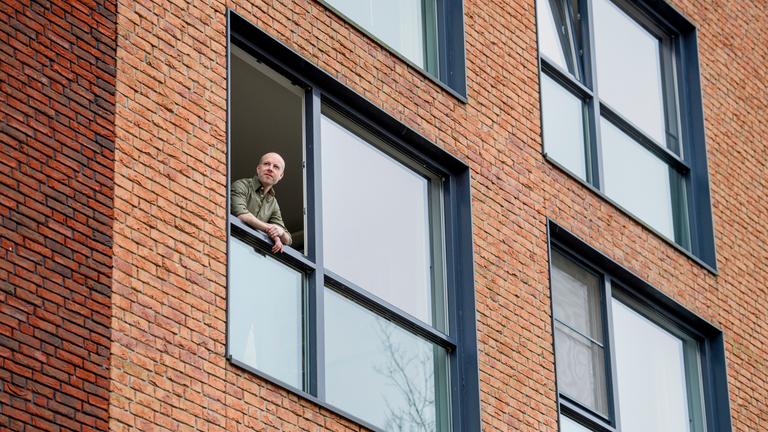 Man kijkt uit raam van apartement