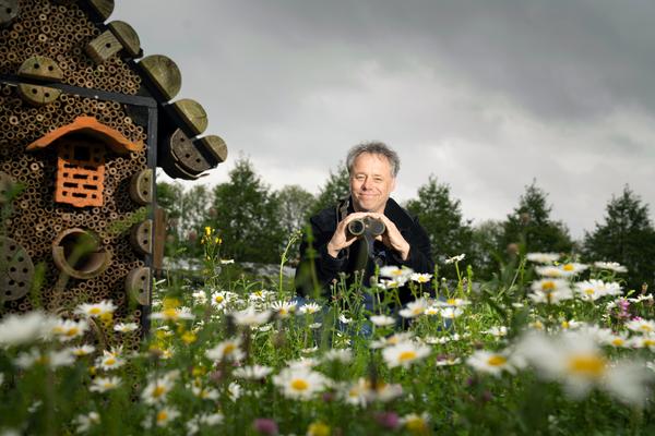 Eneco-ecoloog Luc Hoogenstein in een bloemenveld met verrekijker