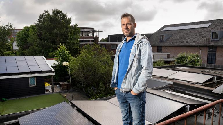 Eneco klant staat op het dak van zijn huis tussen zonnepanelen