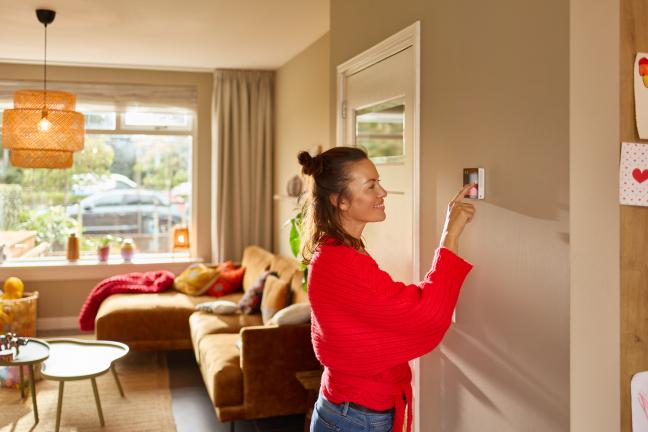 vrouw stelt de thermostaat in