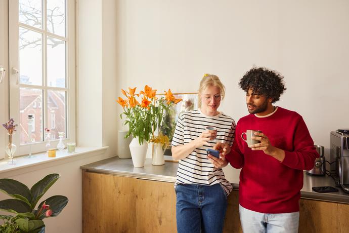 Man en vrouw drinken koffie en kijken op een smartphone