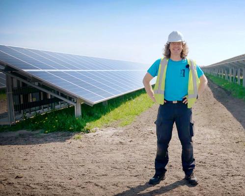 Man met helm staat tussen zonnepanelen