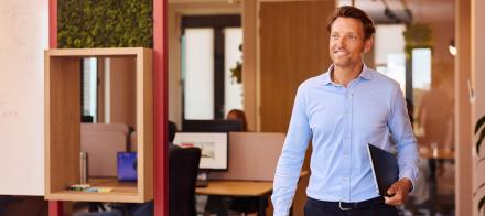 Man op kantoor met laptop onder de arm