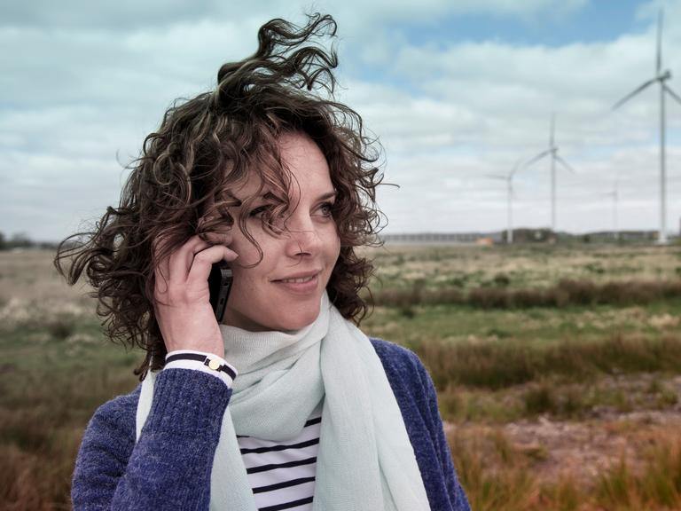 Woman calling outside with wind turbines in the background