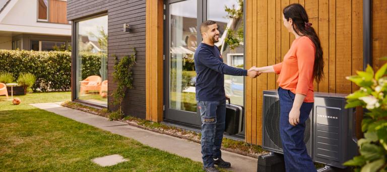 Vrouw schudt de hand van monteur na de installatie van de huur warmtepomp