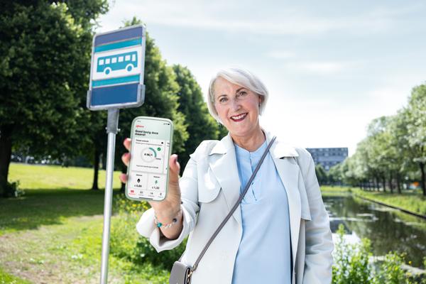 Vrouw met smartphone aan de bushalte