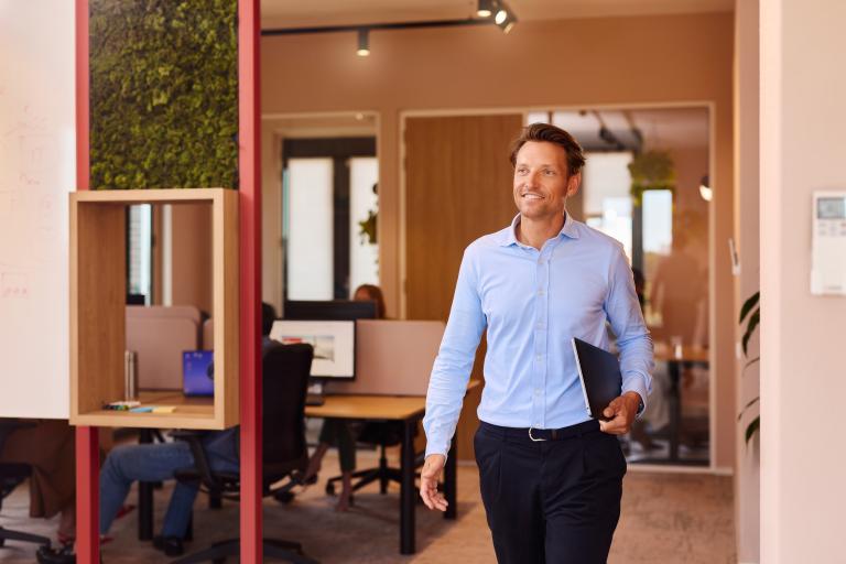 Lachende zakenman met een laptop onder zijn arm