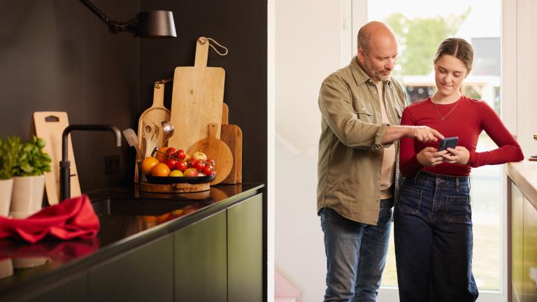 Vader en dochter kijken in de keuken op een smartphone