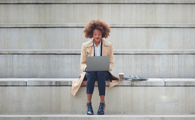 Vrouw met laptop zittend op een betonnen trap