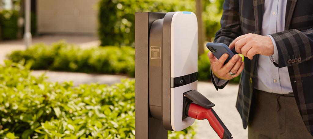 man op de mobiel bij een donkergrijze laadpaal met aangesloten auto