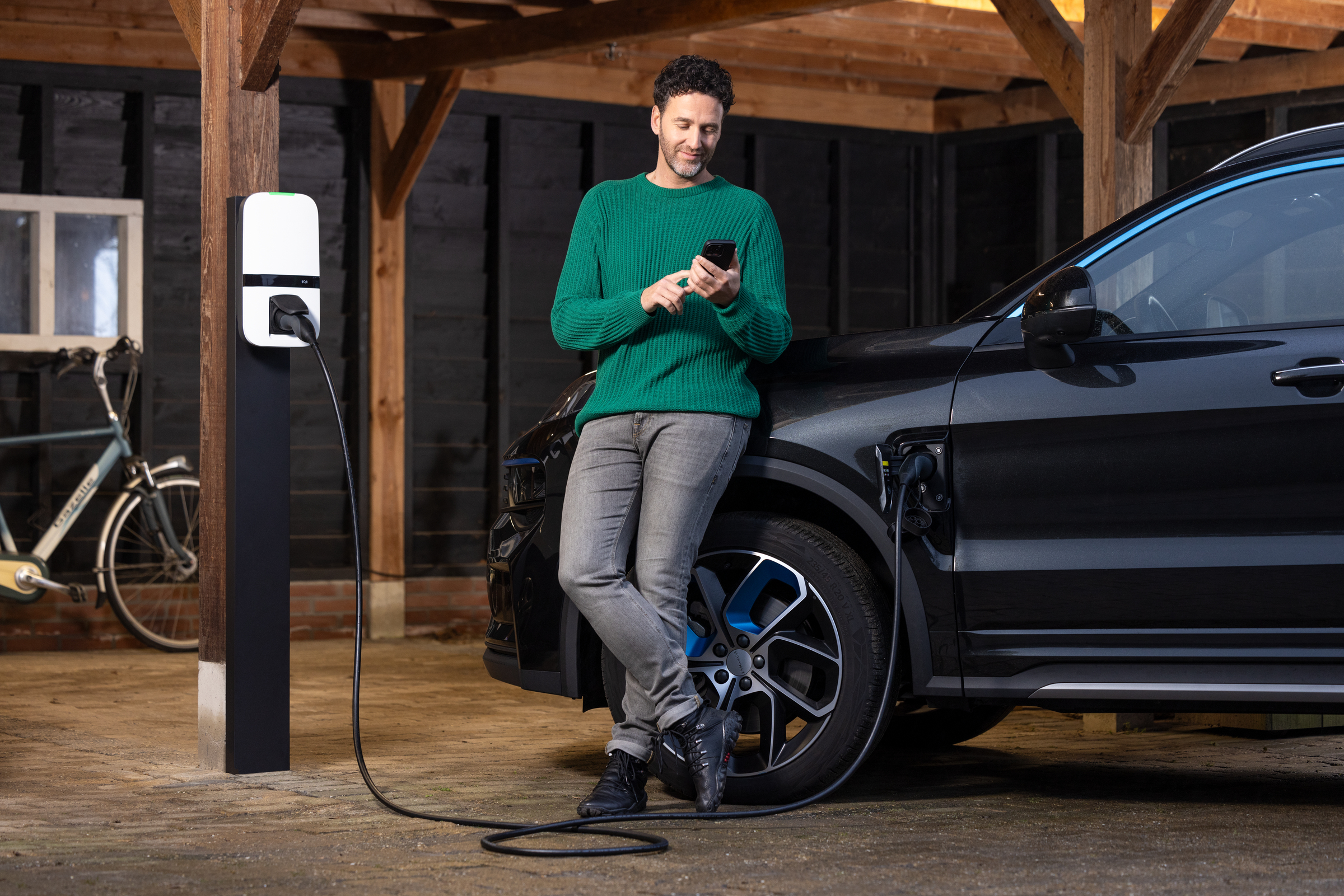 Man controleert zijn verbruik terwijl zijn elektrische wagen oplaadt