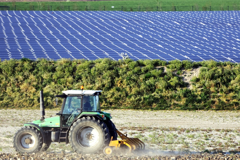 Een tractor naast een zonnepark in Tholen