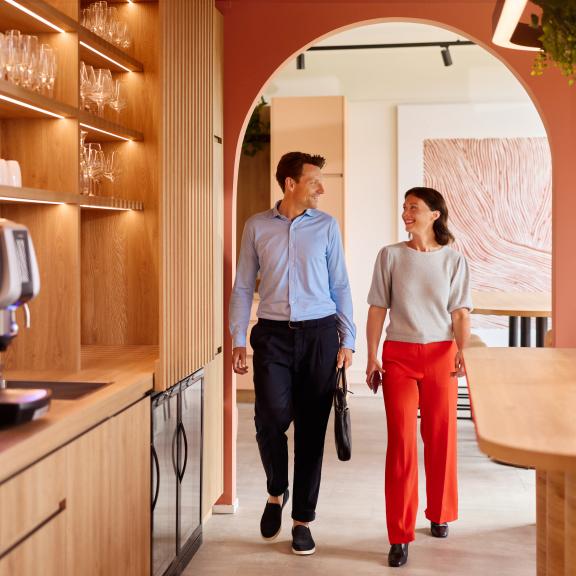 Zakenman en zakenvrouw lopen door de hal en kijken elkaar in de ogen.