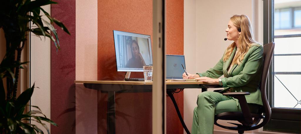 Vrouw zit aan bureau in digitale meeting