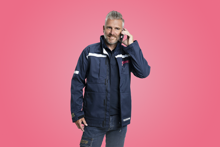 A mechanic in Eneco work clothing is making a phone call