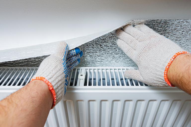 Handen in werkhandschoenen onderhouden een airconditioner met gereedschap