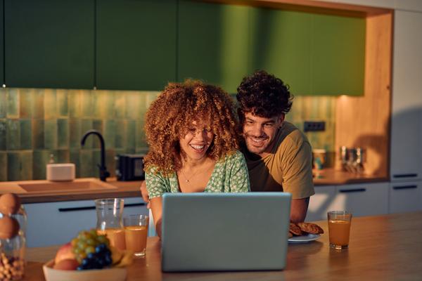 Un couple regarde avec bonheur l'écran d'un ordinateur portable