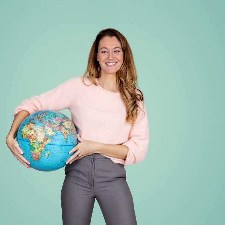 Lachende vrouw met een globe onder haar arm